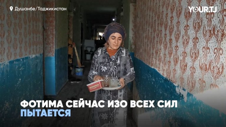 Женщина несет посуду в старом общежитии в Душанбе