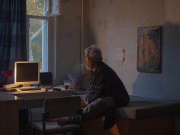 Санкт-Петербург, Россия - 21 октября 2023: Зафархон Мирсолиев курит у себя в комнате возле своего рабочего места, Санкт-Петербург.